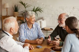 A group of older people at home talking at a table