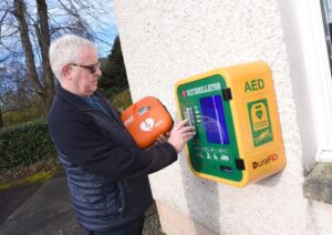 Pictured Martin Stuart, Treasurer for Friends of Forth Valley First Responders, places a defibrillator into a public access box.