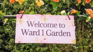 Hanging sign from Garden Arch reads "welcome to ward 1 garden"